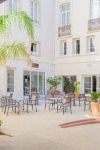 eine Terrasse mit Tischen und Stühlen vor einem Gebäude in der Unterkunft Hôtel IMPERATOR Béziers in Béziers