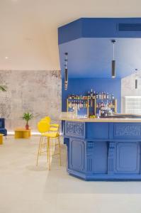 un bar bleu avec des chaises jaunes et un mur bleu dans l'établissement Hôtel IMPERATOR Béziers, à Béziers
