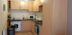 cocina con armarios de madera, lavadora y secadora en Sun Gardens Serviced Apartment, en Thornaby on Tees