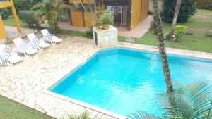 a swimming pool with chairs and a palm tree at Vila da Praia in Boicucanga