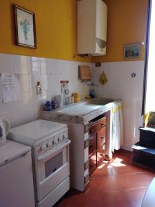Il comprend une cuisine équipée d'une cuisinière blanche et d'un évier. dans l'établissement Appartamento Oleandro, à Montale