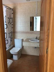 uma casa de banho com um WC, um lavatório e um espelho. em Villa Sunshine em Corralejo
