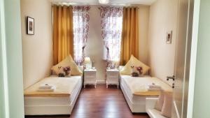 two beds in a room with two windows at Appartements am Bachhaus in Eisenach