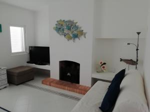 a white living room with a couch and a television at Jasmim in Lagos
