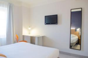 a hotel room with a bed and a tv on the wall at Hôtel IMPERATOR Béziers in Béziers