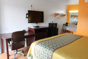 Dormitorio con cama, escritorio y TV en Lone Star Inn Kerrville/Fredericksburg, en Kerrville