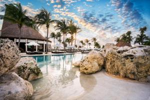 una piscina en un complejo con palmeras y rocas en Secrets Maroma Beach Riviera Cancun - Adults only, en Playa del Carmen