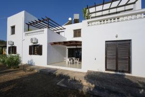 a white house with a black door and a table at Bayview Apartments in Agios Nikolaos