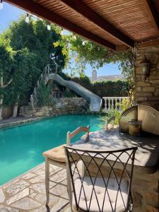 a pool with a slide and a table and chairs at Under the Tuscan Sun Cottage in West Los Angeles in Los Angeles