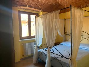 een slaapkamer met een hemelbed en een raam bij Alloggio Berenice in Villafranca Piemonte