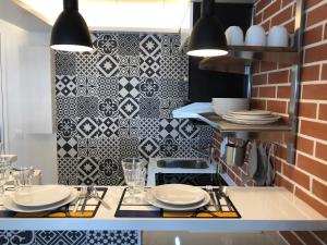 a kitchen with black and white tile on the wall at Appartement Hainaut Paris XIXème- Tout Equipé! in Paris