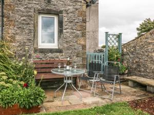 a patio with a table and chairs and a bench at 3 Moorview in Buxton