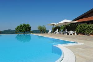 a swimming pool with chairs and umbrellas next to a house at Belica Bed and Breakfast in Dobrovo