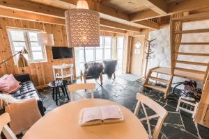 a room with a table and chairs and a cow in the background at The View in Bøur