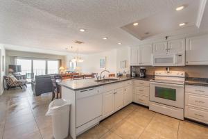 a kitchen with white cabinets and a living room at 207 Beach Place Condos in St. Pete Beach