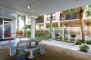 eine Terrasse mit einem Tisch und Bänken vor einem Gebäude in der Unterkunft Luxury Direct Beachfront Views - Crimson #201 in St Pete Beach