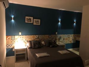 a bedroom with a bed and a blue wall at Pousada Manjericão in Guaramiranga