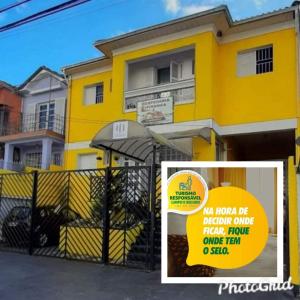 une maison jaune avec une clôture devant elle dans l'établissement Hospedaria Ipiranga, à São Paulo