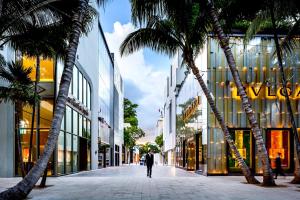 a man walking down a street in front of a building with palm trees at Experience the perfect Miami Life!! Centrally located Luxury Condo! in Miami