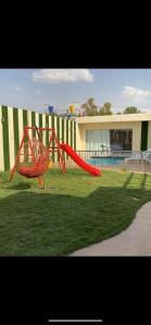 a red slide in the grass in a yard at Sydra Chalet in Riyadh