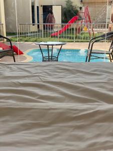 a table and chairs next to a pool with a playground at Sydra Chalet in Riyadh