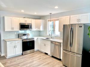 uma cozinha com armários brancos e um frigorífico de aço inoxidável em The Longmont Luxury Condo in the heart of providence em Providence