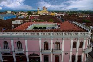 een roze gebouw met een stad op de achtergrond bij Hotel Real La Merced in Granada