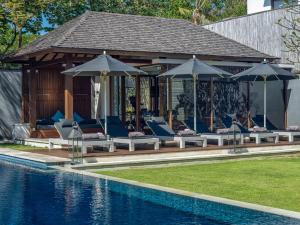 a pavilion with chairs and umbrellas next to a pool at Villa Cendrawasih in Seminyak
