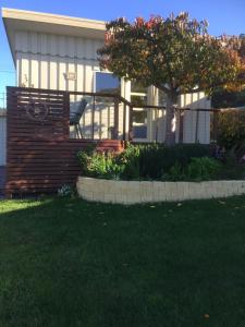a house with a fence and a tree in the yard at Wheel House Studio in Bicheno