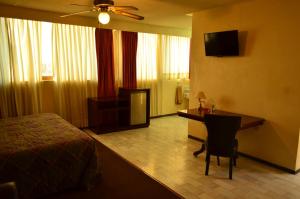 Habitación de hotel con cama, escritorio y TV. en Hotel Flamingo Kristal, en Irapuato
