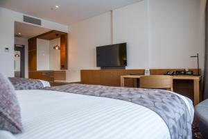 a hotel room with a bed and a flat screen tv at Mercure Sydney Liverpool in Liverpool