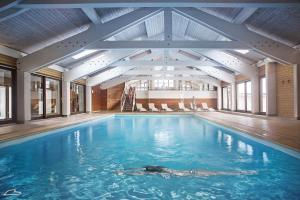 a large swimming pool with blue water in a building at Hotel Beauregard in La Clusaz