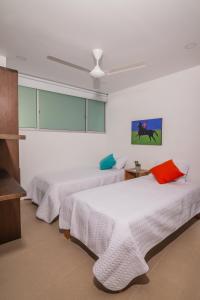 2 Betten in einem Zimmer mit weißen Wänden in der Unterkunft Magico Apartamento Frente al Mar 3 Habitaciones MSC22 in Coveñas