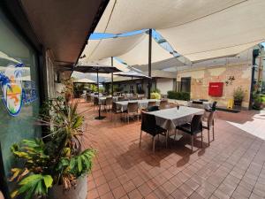ein Restaurant mit Tischen, Stühlen und Sonnenschirmen in der Unterkunft Hotel Allen in Townsville
