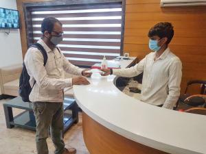 twee mannen aan een balie met maskers op bij Airport Hotel Delhi Aerocity in New Delhi