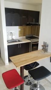 een keuken met een houten tafel en twee rode stoelen bij Apartamento Armenia, como en casa! in Armenia
