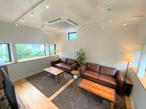 B&B KAMAKURA في كاماكورا: غرفة معيشة مع كنبتين جلديتين وطاولة