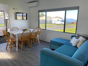 a living room with a blue couch and a table and chairs at Swansea Holiday Park Tasmania in Swansea