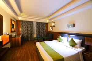 una habitación de hotel con una cama grande y una silla en Gokulam Park Hotel & Convention Centre, en Kochi