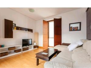 een woonkamer met een witte bank en een tv bij Atico padre Aldama in Sanlúcar de Barrameda