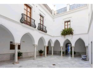 een groot wit gebouw met een binnenplaats met potplanten bij Atico padre Aldama in Sanlúcar de Barrameda