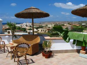 un patio con sedie, tavoli e ombrelloni di Hotel Il Faro Della Guitgia Tommasino a Lampedusa