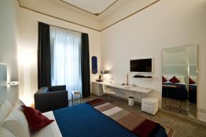 a hotel room with a bedroom with a desk and a bed at Town House Cavour in Reggio di Calabria