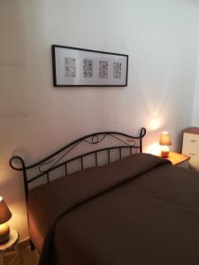 a bedroom with a bed with two lamps and a picture on the wall at Solemar in San Vito lo Capo