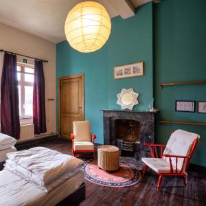 a bedroom with a bed and chairs and a fireplace at Kasteel Nieuwenhoven in Sint-Truiden