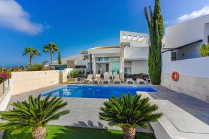 eine Villa mit einem Pool und Palmen in der Unterkunft Villa Caterina, Luxury Villa with Heated Pool Ocean View in Adeje, Tenerife in Adeje