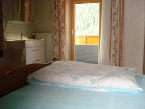 Bett in einem Zimmer mit Fenster und Tagesdecke in der Unterkunft Haus Walter in Nesselwängle