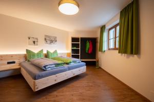 ein Schlafzimmer mit einem Bett mit grünen Kissen und einem Fenster in der Unterkunft Ferienwohnung Carmen Schuchter in Vandans