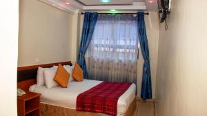 sypialnia z łóżkiem i oknem z niebieskimi zasłonami w obiekcie Sheratton Regency Hotel Nairobi w mieście Nairobi