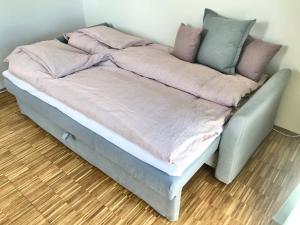 a bed with pink and grey blankets and pillows at Villa Stjerneklar in Copenhagen